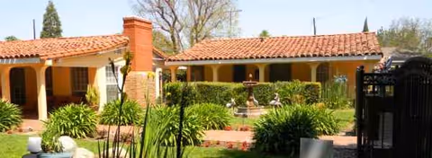 Front exterior of The Villa Senior Home with arches and a manicured courtyard.