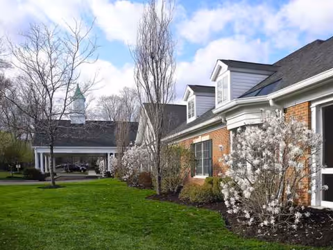 Exterior view of The Greens at Greenwich with a green lawn and blooming shrubs.
