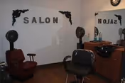 Small salon room with styling chairs, hooded hair dryers, a sink and mirror, and the word 'SALON' on the wall.