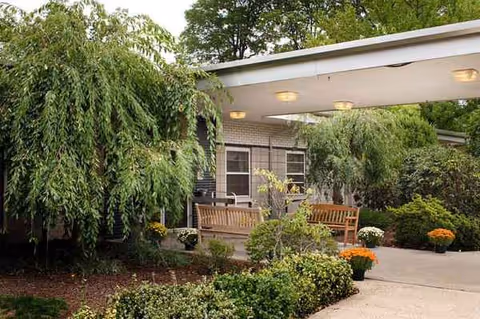 Exterior covered walkway with benches and greenery at Troy Hills Center senior living