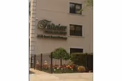 Exterior view of a beige building with Fairview Rehab & Nursing Home sign and landscaped entrance.