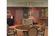 Interior common area with a round table and chairs in front of decorative furniture and a wall sign reading "Forest Haven".