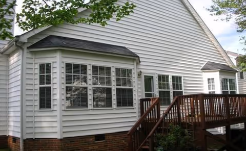 White suburban-style building exterior with large windows and a wooden deck staircase.