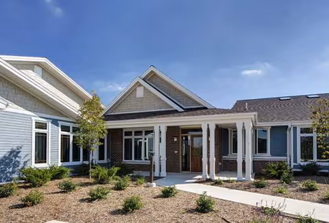 Exterior view of Linden Court New Berlin with brick entrance, white columns, and landscaped front yard.