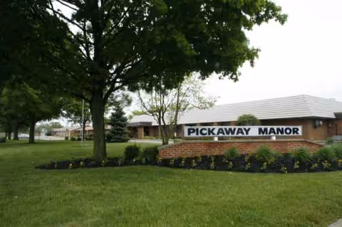Exterior view of Cranberry Park at Pickaway Manor with a sign, brick border, and green lawn.