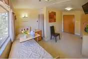 Bright bedroom in a McClure Post Acute facility with bed, table, chair, and window.