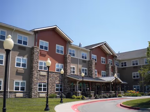 Exterior view of a multi-story senior living facility with entrance and curved walkway.