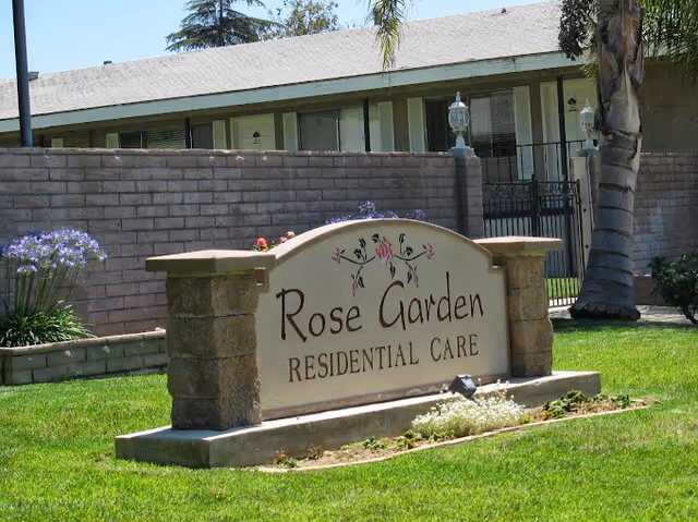 Stone sign reading Rose Garden Residential Care sits on a lawn in front of a building