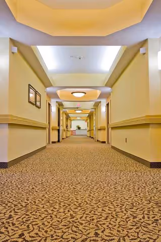 Long, well-lit Crestview Court hallway with beige walls, patterned carpet, and doors along both sides.