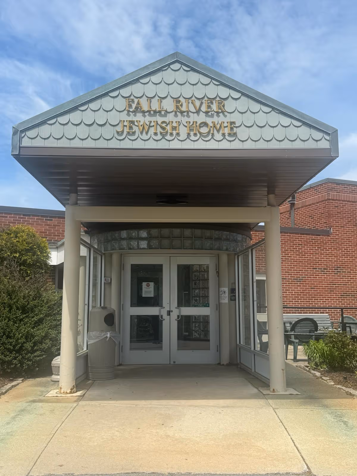 The entrance canopy and double glass doors of the Fall River Jewish Home with the facility name displayed above.