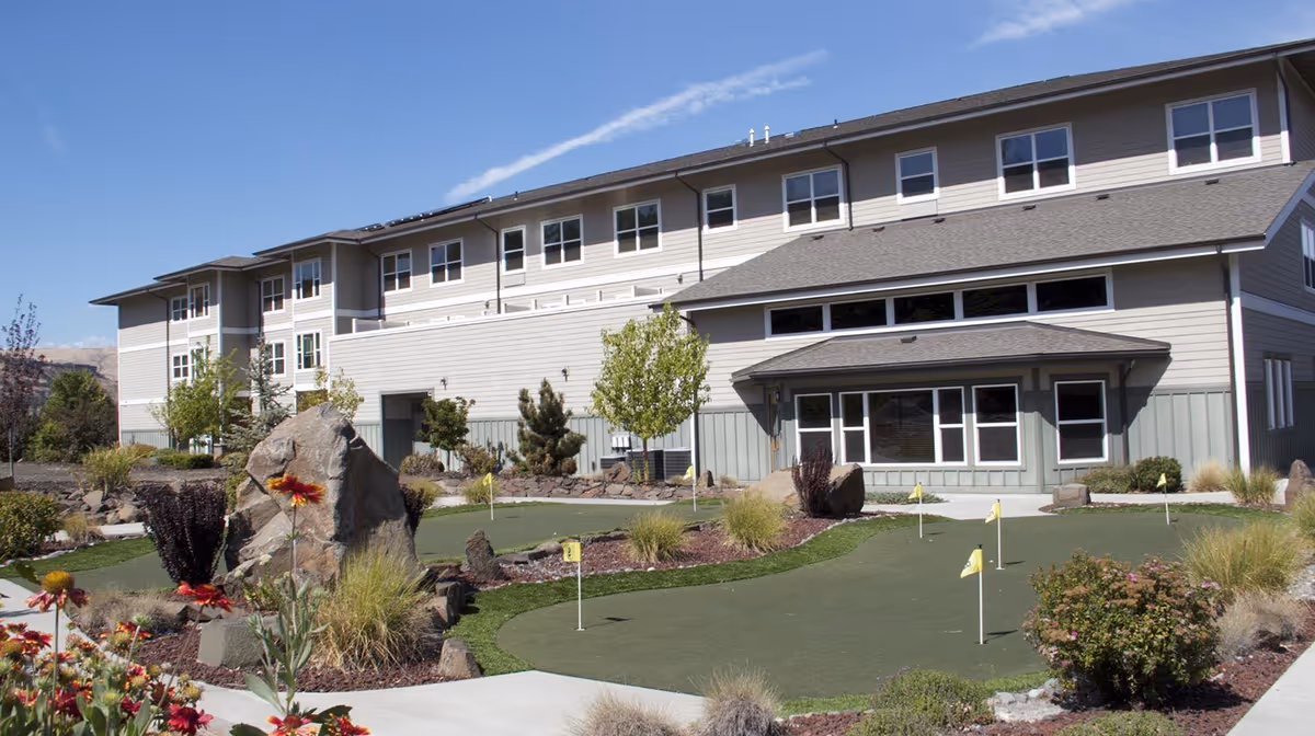 Exterior view of The Springs at Mill Creek building with a landscaped courtyard and small putting green in front.