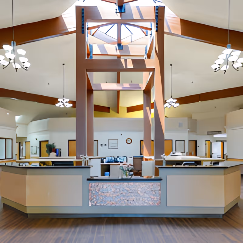 Spacious skylit lobby with a central reception desk, high ceilings and hanging light fixtures.