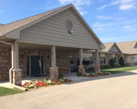 Exterior view of Ripon Senior Living facility with entrance, pillars, and flower beds