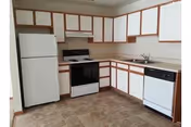 U-shaped kitchen with white cabinets trimmed in wood, a refrigerator, stove, dishwasher, and sink.
