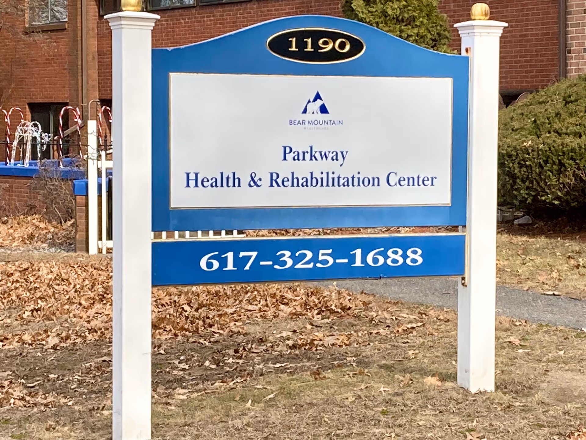Blue and white sign in front of a brick building reading 'Parkway Health & Rehabilitation Center' with address number 1190 and phone 617-325-1688.