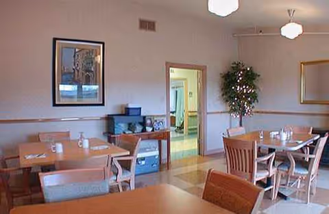 Regency Albany senior living dining room with wooden tables, chairs, and ambient lighting.