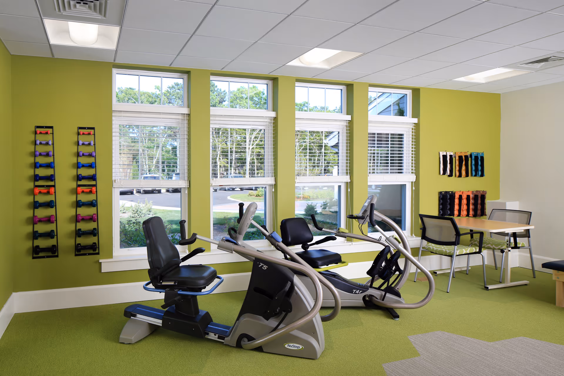 Maplewood at Brewster fitness room with stationary bikes, dumbbells, and a seating area.
