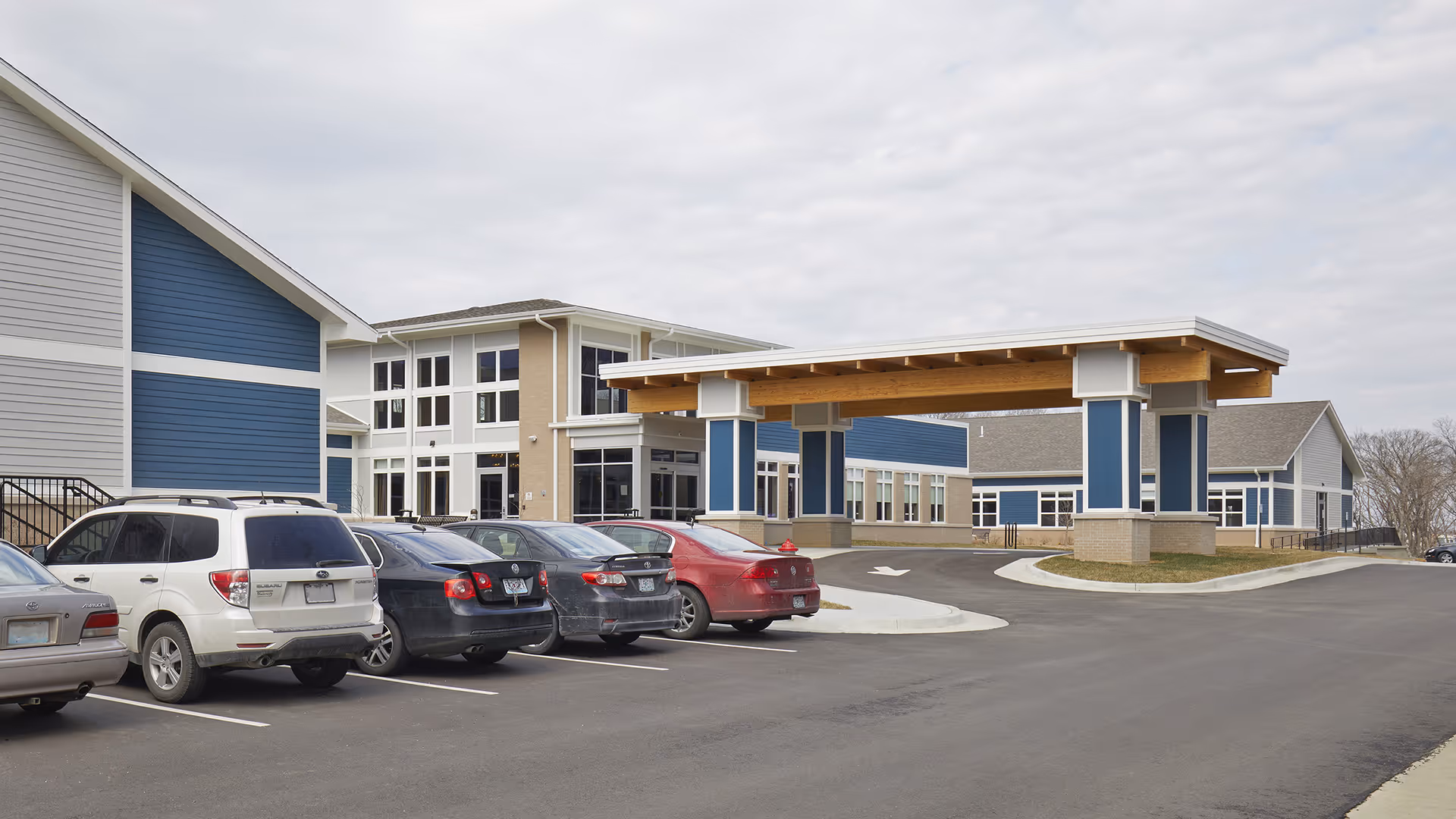 Exterior front entrance of Columbia Post Acute showing a covered porte-cochère, building facade, and parked cars in the lot.