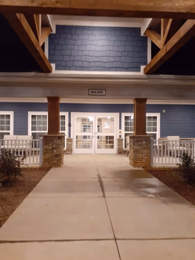 Covered entrance walkway leading to glass double doors labeled "Main Entry" at the front of the building.