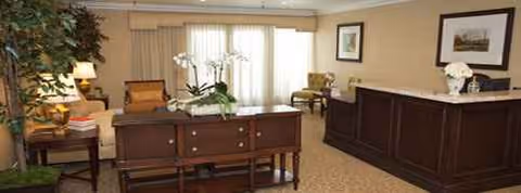 Lobby area with a reception desk, seating, plants, and framed artwork.