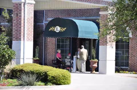 Front entrance of The Ridge at Frisco with green awning and residents gathered outside