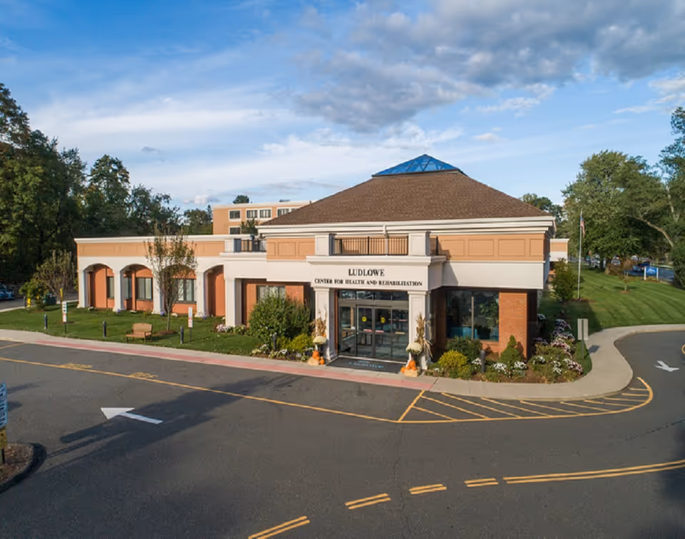 Exterior view of Ludlowe Center for Health and Rehabilitation with a brick entrance and landscaping.