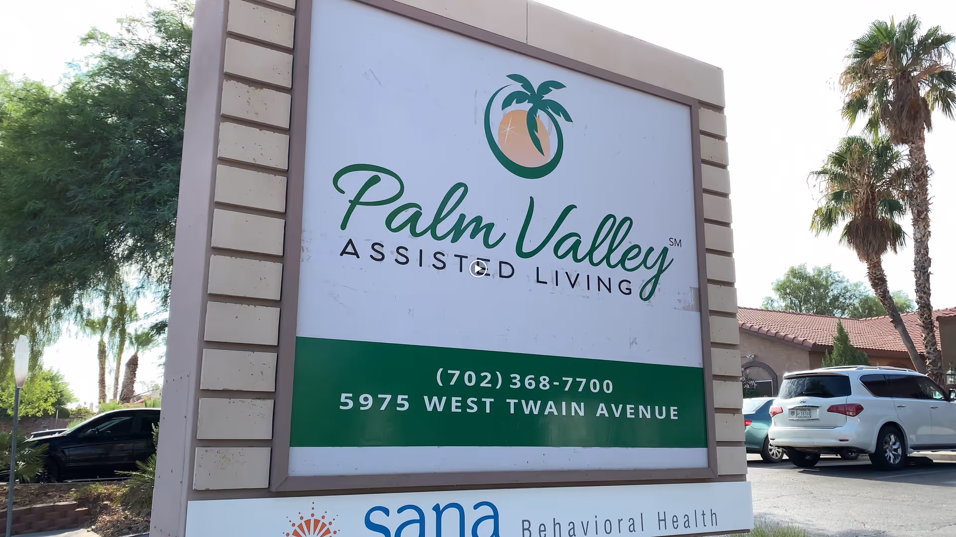 Outdoor sign for Palm Valley Assisted Living located at 5975 West Twain Avenue, with parked cars and palm trees in the background.