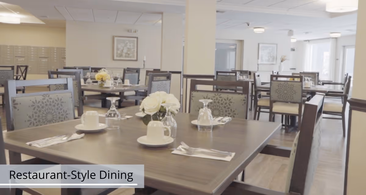 Well-lit restaurant-style dining room with multiple set tables, chairs, and floral centerpieces.