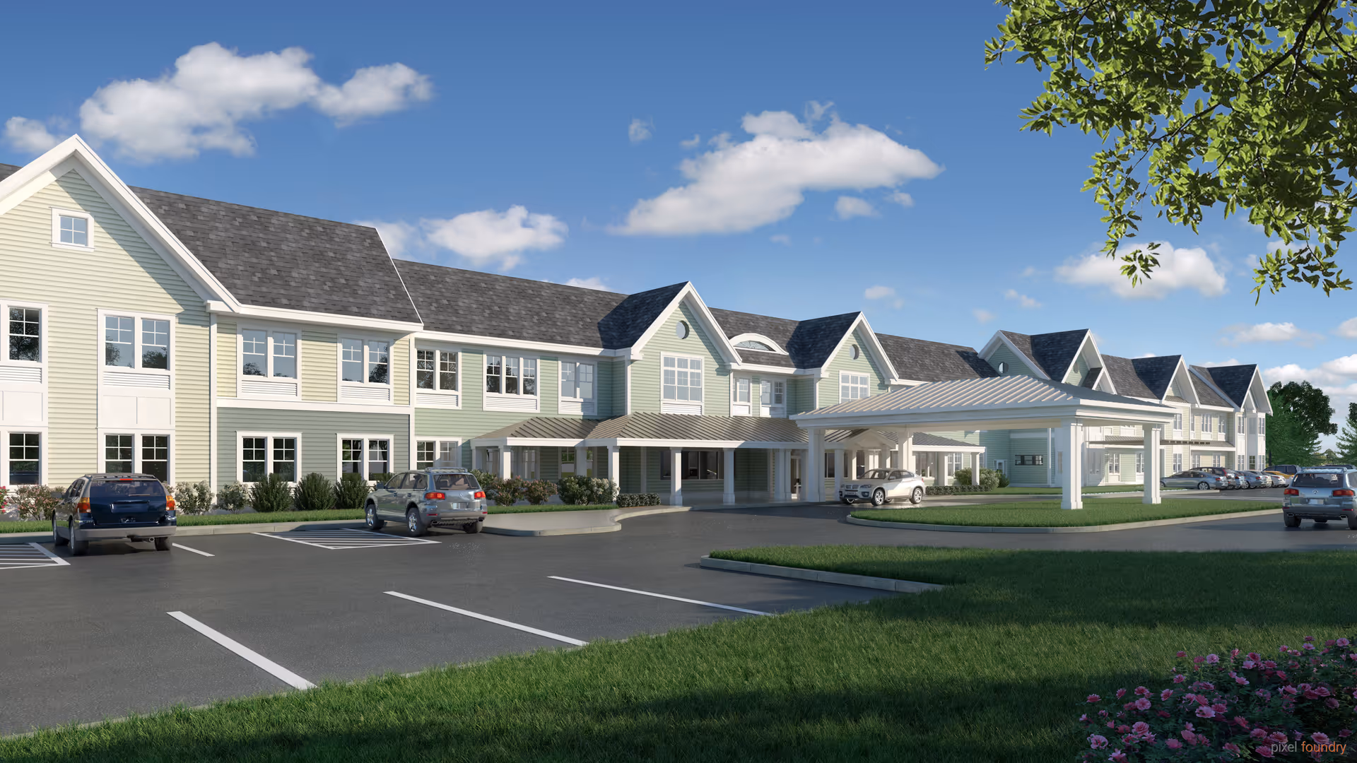 Exterior view of a large two-story senior living facility building with light green siding and multiple windows under a blue sky with scattered clouds. There is a covered entrance with a white canopy, a parking lot with several cars, green grass, and some flowering plants in the foreground.