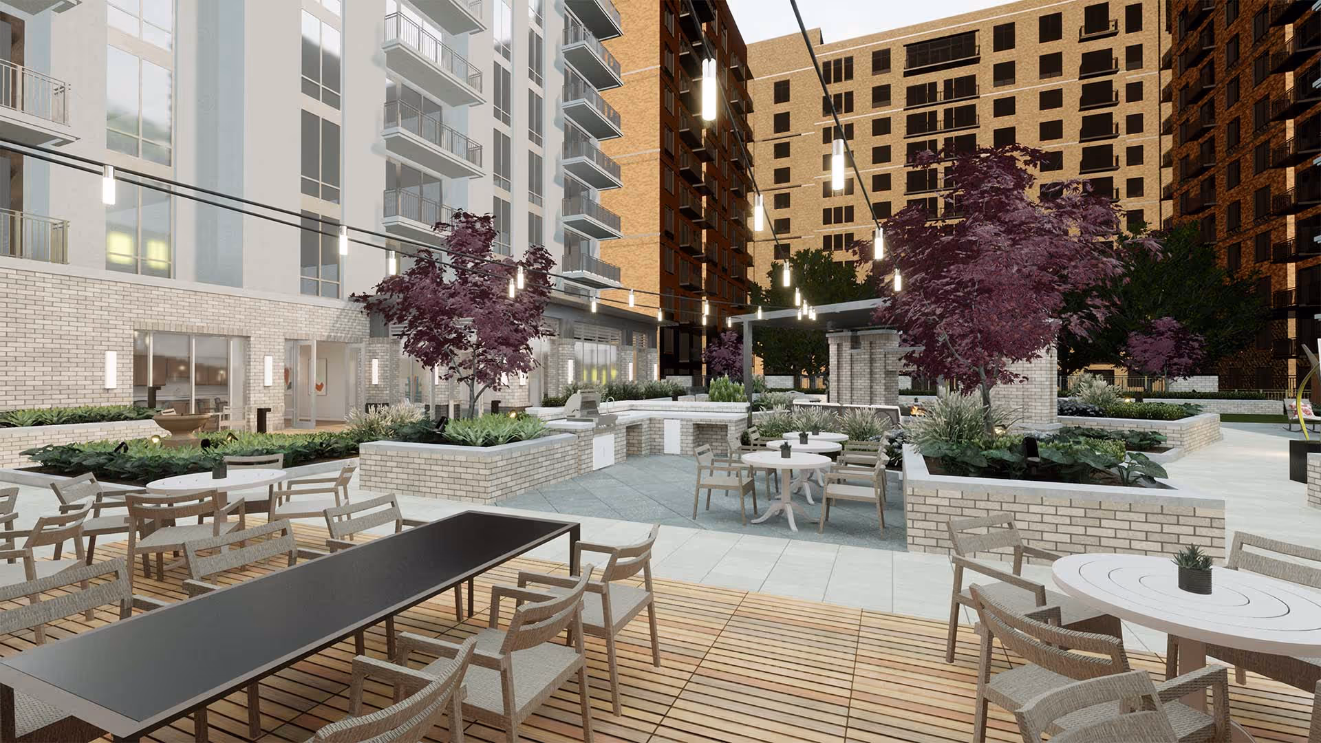 Outdoor courtyard area of a senior living facility with multiple seating arrangements including tables and chairs, surrounded by raised garden beds with plants and purple-leafed trees. The space is lit by hanging string lights and is enclosed by multi-story residential buildings.