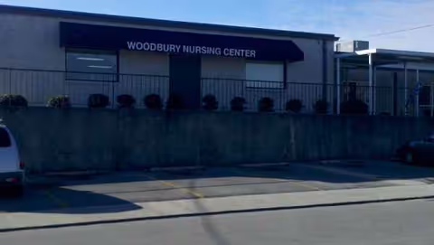 Exterior view of Woodbury Nursing Center with entrance, sign, and parking lot.