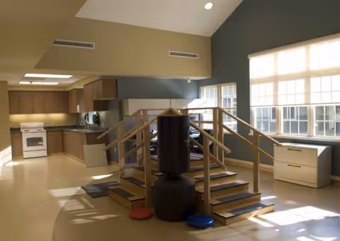Interior common area with kitchen in background, raised exercise platform, and a punching bag.