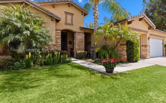 Exterior of Cathy's Cottage Assisted Living and Memory Care showing a manicured lawn and palm trees.