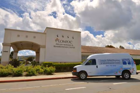Exterior view of Lompoc Skilled Nursing & Rehabilitation Center with a white van parked in front.