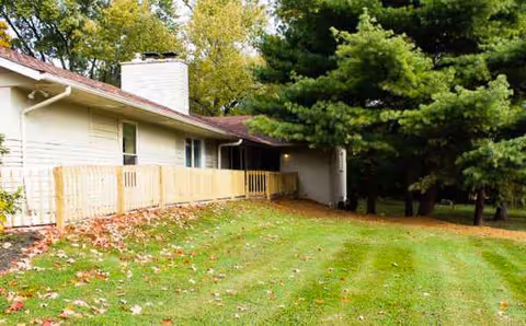Exterior view of a single-story facility with a grassy yard and trees