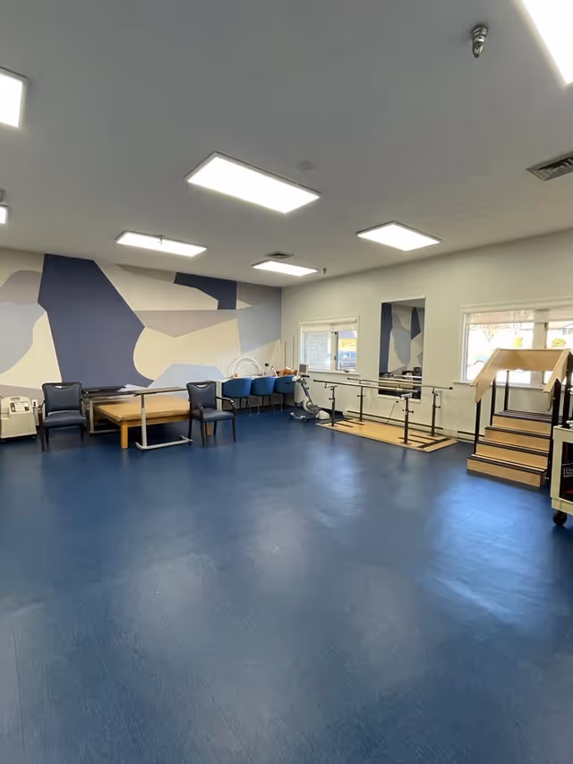 Spacious interior therapy area in a senior facility with blue floor and wall mural.