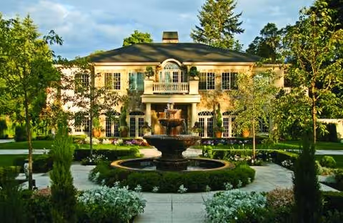 Front view of Kensington Gardens Resort Living exterior with a central fountain and manicured landscaping.