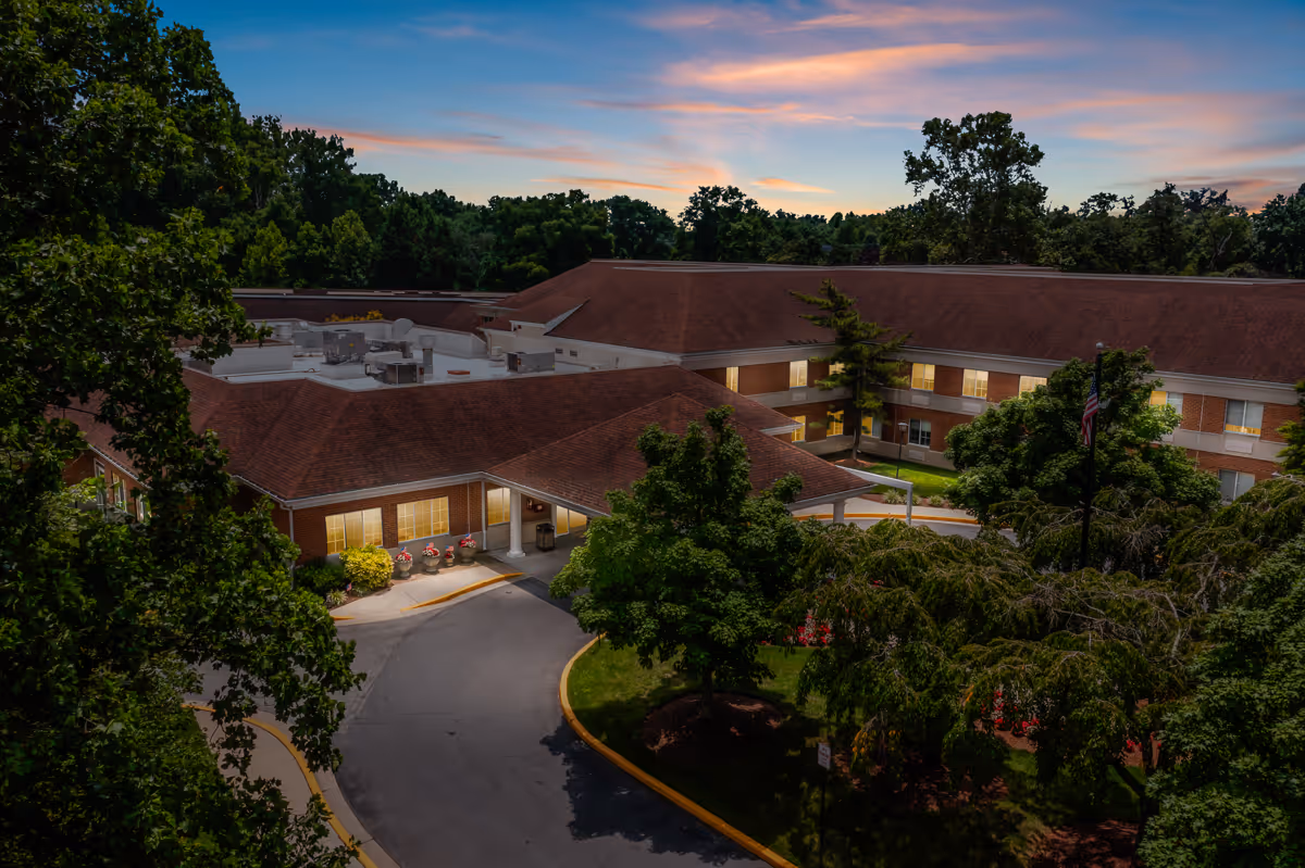 Aerial view of Autumn Lake Healthcare at Silver Spring building at dusk, surrounded by trees and greenery with a curved driveway leading to the entrance.