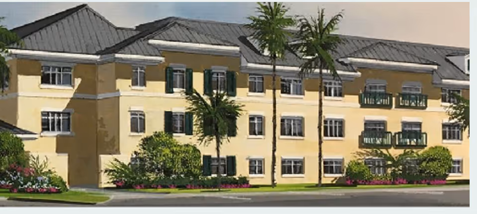 Exterior view of a three-story senior living community building with yellow walls, green window shutters, balconies, palm trees, and landscaped bushes and flowers in front.