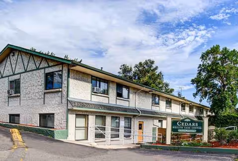 Front view of Cedars Health Care Center building with sign and parking area.