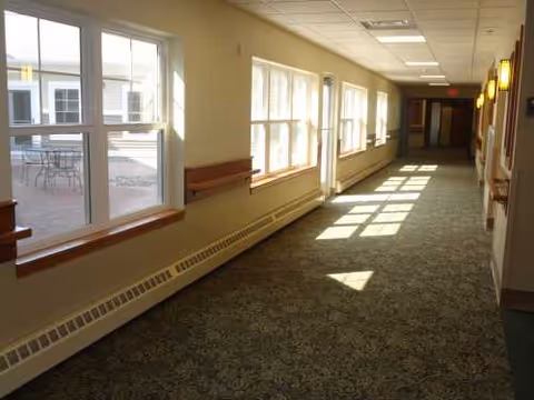 Long indoor hallway at Lawson Manor with windows, benches, and patterned carpet.