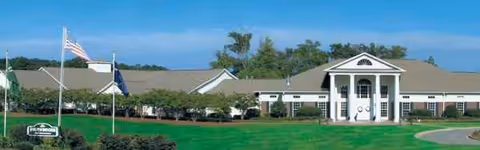 Front view of Generations of Chapin senior living facility with flags and manicured lawn.