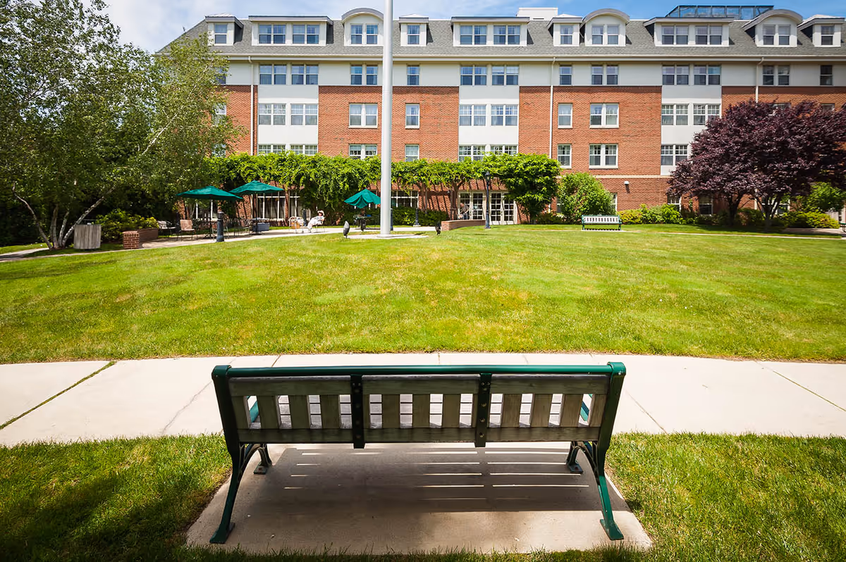 Front view of Providence House Assisted Living building with green lawn and benches.