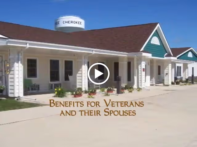 Front exterior of a single-story assisted living building with a covered porch and a text overlay about benefits for veterans and their spouses.