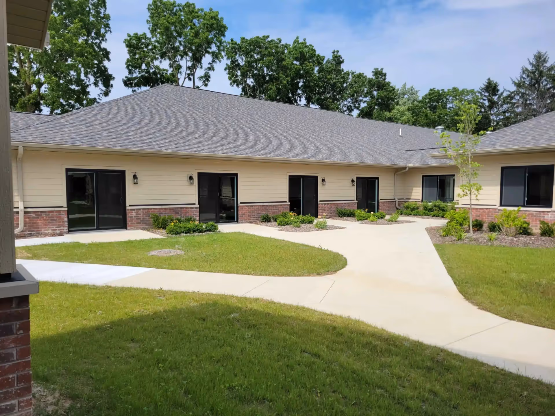 Single-story assisted living building with curved walkway and landscaped entrances.