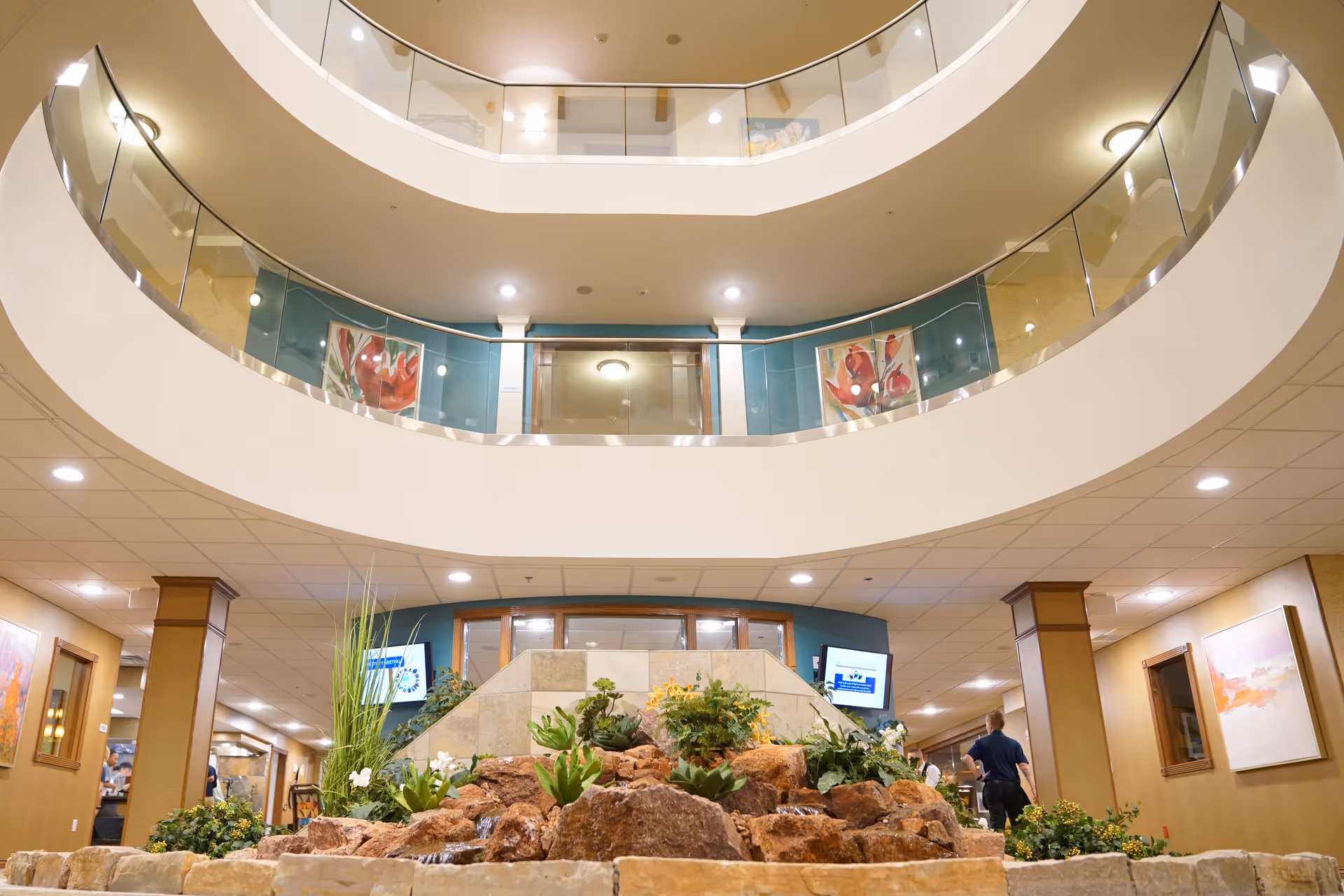 Interior atrium with curved balconies, glass railings, and an indoor rock garden beneath.