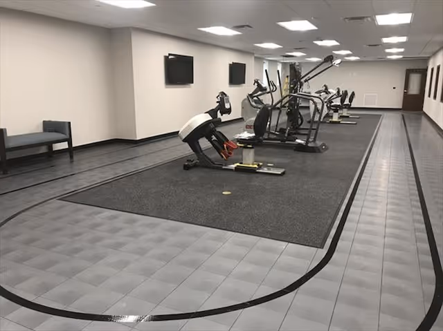 Fitness room with exercise machines, an indoor walking track, and wall-mounted TVs.