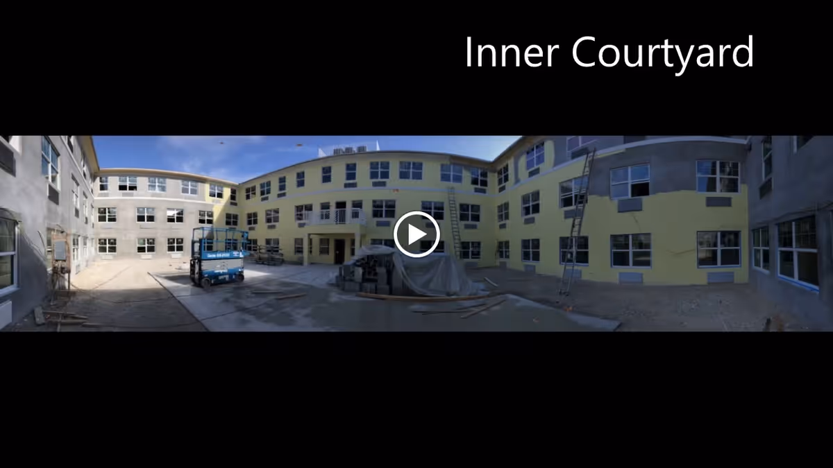 Panoramic view of an inner courtyard of a multi-story senior living building under construction.