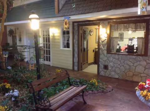Exterior view of Rosemore Village featuring a bench, garden, and entrance doorway.