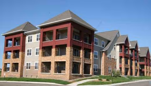 Exterior view of a multi-story senior living building with brick and red accents.